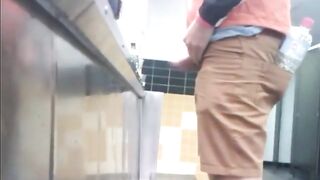 Guys in the urinals taking leak.